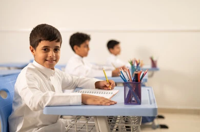 الإستعداد للعام الدراسي الجديد، تأدية الواجبات المدرسية، التعليم في السعودية، العودة إلى المدارس، مجموعة من الطلاب العربيين الخليجيين السعوديين يرتدون الزي التقليدي  يجلسون في مقاعدهم ويقومون بحل الواجب
