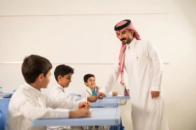حوارات ودية بين الاستاذ والطلاب، جودة التعليم في السعودية، معلم عربي خليجي سعودي يرتدي الثوب التقليدي والشماغ يقوم بمناقشة الدروس مع طلابه، مجموعة من طلاب عربيين خليجيين سعوديين يرتدون الزي المدرسي يقومون بتأديه الواجبات ، المشاركة الفعالة للطلاب مع المدرسين، التربية والتعليم بالمناهج المقررة للتلاميذ
