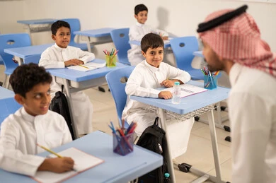 المشاركة الفعالة للطلاب مع المدرسين، التربية والتعليم بالمناهج المقررة للتلاميذ، جودة التعليم في السعودية، معلم عربي خليجي سعودي يرتدي الثوب التقليدي والشماغ يقوم بمناقشة الدروس مع طلابه، مجموعة من طلاب عربيين خليجيين سعوديين يرتدون الزي المدرسي يقومون بتأديه الواجبات ،حوارات ودية بين الاستاذ والطلاب