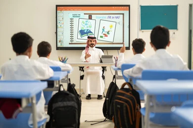 طالب عربي خليجي سعودي مبتسم يرتدي الثوب التقليدي يرفع يديه للإجابة، التفاعل والمشاركة داخل الفصل الدراسي، التربية والتعليم بالمناهج المقررة للطلاب في المملكة العربية السعودية،تعابير وايماءات الحماس لمعرفة الجواب الصحيح