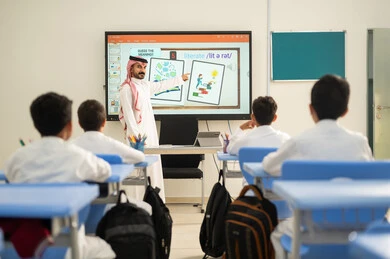 تطور طرائق التدريس في مدارس المملكة،الاستفادة من التقنيات المتطورة في التعلم والدراسة، المناهج المطورة والتعليم الالكتروني، طلاب عربيين خليجيين سعوديين يجلسون في مقاعدهم وأمامهم مدرس سعودي يستخدم السبورة فى الشرح