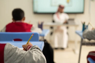 طلاب عربيين خليجيين سعوديين يجلسون في مقاعدهم وأمامهم مدرس سعودي يستخدم السبورة الالكترونية وجهاز التابلت فى الشرح، تطور طرائق التدريس في مدارس المملكة،الاستفادة من التقنيات المتطورة في التعلم والدراسة، المناهج المطورة والتعليم الالكتروني