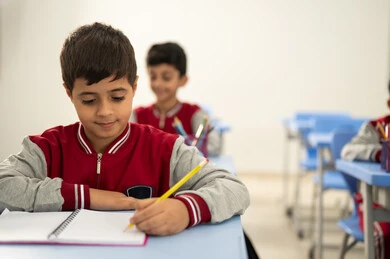 Preparation for the new school year, education in Saudi Arabia, completing school assignments, returning to school, a group of Arab Gulf Saudi students sitting in their seats and doing their homework.