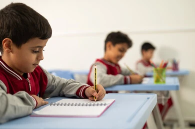 Preparation for the new school year, education in Saudi Arabia, completing school assignments, returning to school, a group of Arab Gulf Saudi students sitting in their seats and doing their homework.