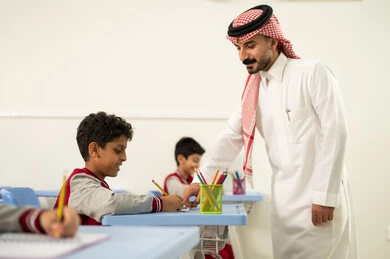 حوارات ودية بين الاستاذ والطلاب، جودة التعليم في السعودية، معلم عربي خليجي سعودي يرتدي الثوب التقليدي والشماغ يقوم بمناقشة الدروس مع طلابه، مجموعة من طلاب عربيين خليجيين سعوديين يرتدون الزي المدرسي يقومون بتأديه الواجبات ، المشاركة الفعالة للطلاب مع المدرسين، التربية والتعليم بالمناهج المقررة للتلاميذ