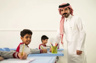 جودة التعليم في السعودية، معلم عربي خليجي سعودي يرتدي الثوب التقليدي والشماغ يقوم بمناقشة الدروس مع طلابه، مجموعة من طلاب عربيين خليجيين سعوديين يرتدون الزي المدرسي يقومون بتأديه الواجبات ، المشاركة الفعالة للطلاب مع المدرسين، التربية والتعليم بالمناهج المقررة للتلاميذ، حوارات ودية بين الاستاذ والطلاب
