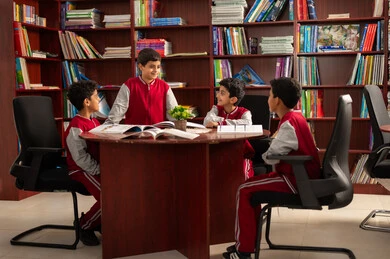 بيئة تعليمية متطورة، مفهوم التعليم الذاتي ،تأدية الواجبات المدرسية ، طلاب عربيين سعوديين خليجيين يرتدون الزي المدرسي يجلسون في المكتبة المدرسية ، الاستمتاع بقراءة الكتب المدرسية، التعليم في المملكة العربية السعودية