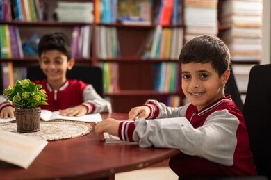 An advanced educational environment, the concept of self-directed learning, completing school assignments, Arab Saudi Gulf students wearing school uniforms sitting in the school library, enjoying reading school books, education in the Kingdom of Saudi Arabia.