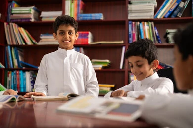 بيئه مدرسيه تعليميه متطوره ، مفهوم التعليم الذاتي,ممارسة هوايه المطالعة، مجموعة من طلاب عربيين خليجيين سعوديين يرتدون الزي التقليدي يجلسون في المكتبة المدرسية، الاستمتاع بقراءة الكتب المدرسية، التعليم في المملكة العربية السعودية