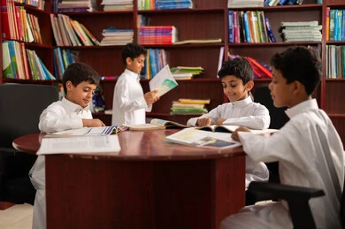 ممارسة هوايه المطالعة، مفهوم التعليم الذاتي, بيئه مدرسيه تعليميه متطوره ، مجموعة من طلاب عربيين خليجيين سعوديين يرتدون الزي التقليدي يجلسون في المكتبة المدرسية، الاستمتاع بقراءة الكتب المدرسية، التعليم في المملكة العربية السعودية