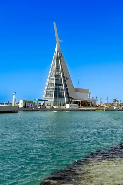 Parks on the waterfront, a charming daytime scene of Jeddah's beach and its distinctive landmarks, the meeting of the clear blue waters of the Red Sea with the wide horizon, a tranquil atmosphere reflecting the beauty of the city of Jeddah and the splendor of its coastal nature.