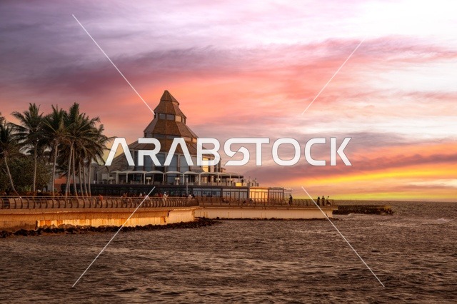 Stunning sunset view over Jeddah beach, with warm colors painting the sky and reflecting on the clouds, creating a breathtaking scene along the Red Sea waterfront.