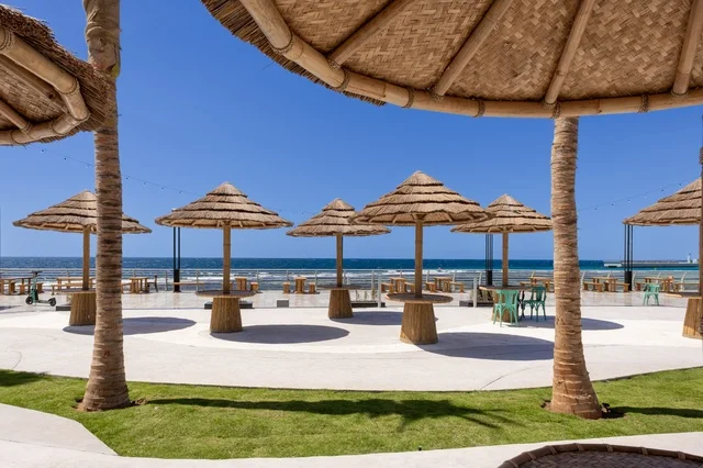 Calm atmosphere reflecting the beauty of the city of Jeddah and the splendor of its coastal nature. A charming daytime scene of Jeddah's beach and its distinctive landmarks, including mosques, hotels, and parks along the waterfront.