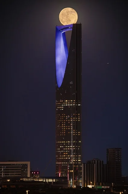 Unique architectural designs and engineering arts for economic buildings and towering skyscrapers, the King Abdullah Financial Center (KAFD) towers in Riyadh, famous tourist spots and destinations, the illuminated economic tower at night with the full moon in the sky of the Kingdom of Saudi Arabia.