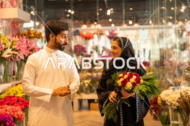 تعابير وايماءات المودة والسعاده، محلات ومتاجر بيع وشراء الورود والزهور الطبيعية للأعياد والمناسبات, زوج عربي خليجي سعودي يرتدي الثوب التقليدي يقوم بإهداء باقة ورد احمر طبيعي لزوجته