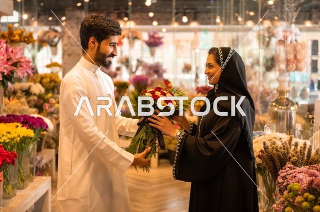 تعابير وايماءات المودة والسعاده، محلات ومتاجر بيع وشراء الورود والزهور الطبيعية للأعياد والمناسبات, زوج عربي خليجي سعودي يرتدي الثوب التقليدي يقوم بإهداء باقة ورد احمر طبيعي لزوجته