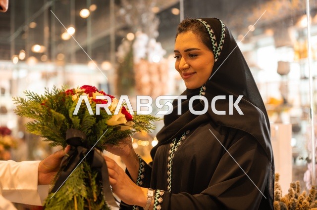 تعابير وايماءات المودة والسعاده، محلات ومتاجر بيع وشراء الورود والزهور الطبيعية للأعياد والمناسبات, زوج عربي خليجي سعودي يرتدي الثوب التقليدي يقوم بإهداء باقة ورد احمر طبيعي لزوجته