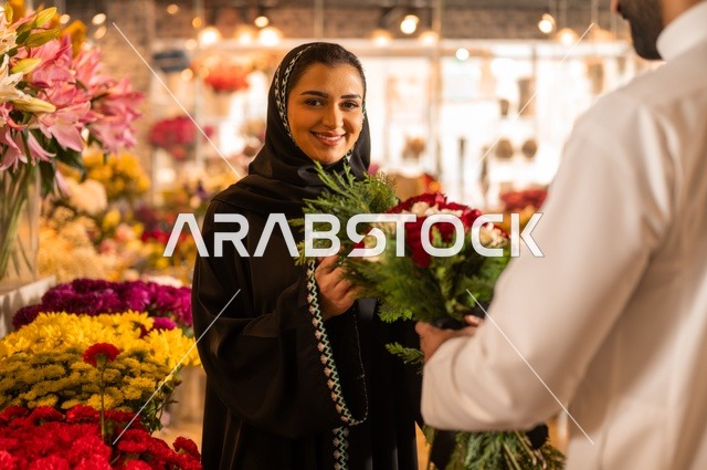تعابير وايماءات المودة والسعاده، محلات ومتاجر بيع وشراء الورود والزهور الطبيعية للأعياد والمناسبات, زوج عربي خليجي سعودي يرتدي الثوب التقليدي يقوم بإهداء باقة ورد احمر طبيعي لزوجته