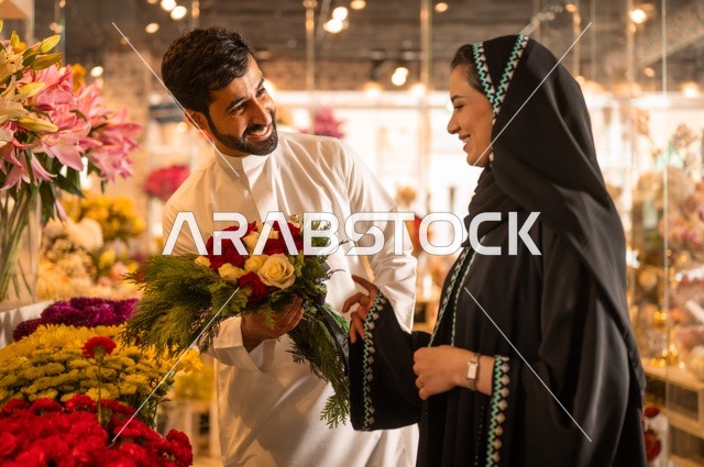 تعابير وايماءات المودة والسعاده، محلات ومتاجر بيع وشراء الورود والزهور الطبيعية للأعياد والمناسبات, زوج عربي خليجي سعودي يرتدي الثوب التقليدي يقوم بإهداء باقة ورد احمر طبيعي لزوجته