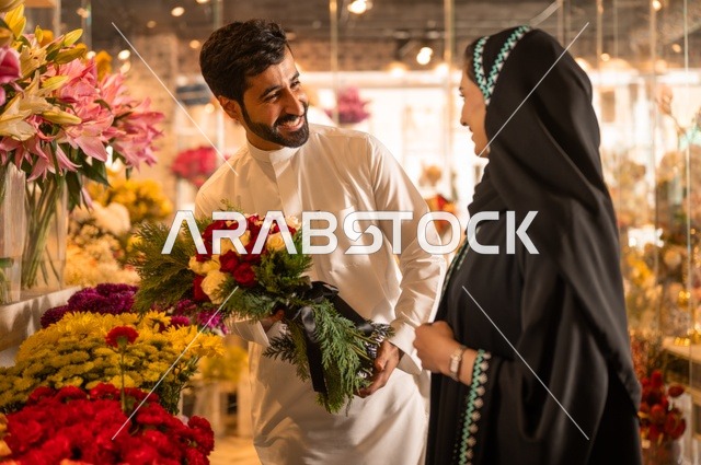 تعابير وايماءات المودة والسعاده، محلات ومتاجر بيع وشراء الورود والزهور الطبيعية للأعياد والمناسبات, زوج عربي خليجي سعودي يرتدي الثوب التقليدي يقوم بإهداء باقة ورد احمر طبيعي لزوجته