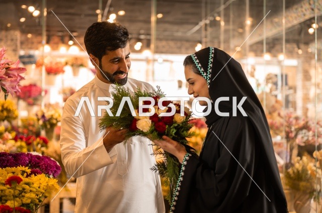 تعابير وايماءات المودة والسعاده، محلات ومتاجر بيع وشراء الورود والزهور الطبيعية للأعياد والمناسبات, زوج عربي خليجي سعودي يرتدي الثوب التقليدي يقوم بإهداء باقة ورد احمر طبيعي لزوجته