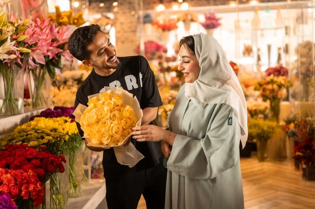 الاختفال بالأعياد والمناسبات الخاصة ، زوج عربي خليجي سعودي يرتدي الزي الكاجوال يقوم بإهداء باقة ورد اصفر طبيعي لزوجته، تعابير وايماءات المودة والسعاده، محلات ومتاجر بيع وشراء الورود والزهور الطبيعية