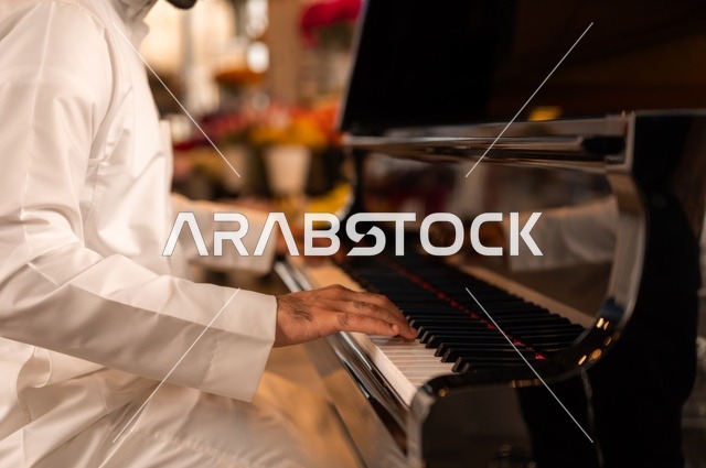 مواهب فنية موسيقية، قضاء الوقت بالعزف على الألات الوترية، الطرب والانشطة ترفيهية، تقديم البرامج والفنون الموسيقية والفن المسرحي، رجل خليجي سعودي عربي فنان يجلس امام آلة البيانو الموسيقية ويستمتع بالعزف