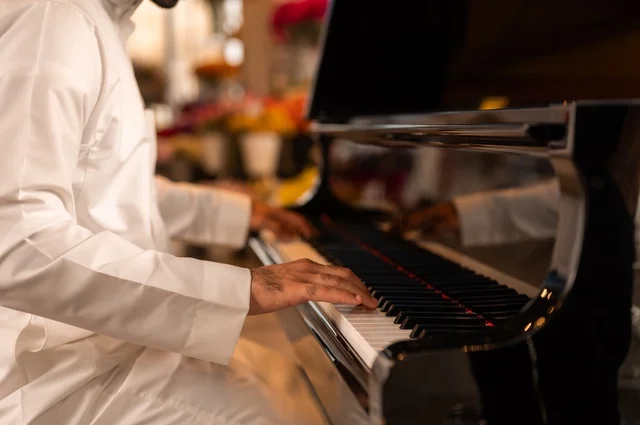 مواهب فنية موسيقية، قضاء الوقت بالعزف على الألات الوترية، الطرب والانشطة ترفيهية، تقديم البرامج والفنون الموسيقية والفن المسرحي، رجل خليجي سعودي عربي فنان يجلس امام آلة البيانو الموسيقية ويستمتع بالعزف