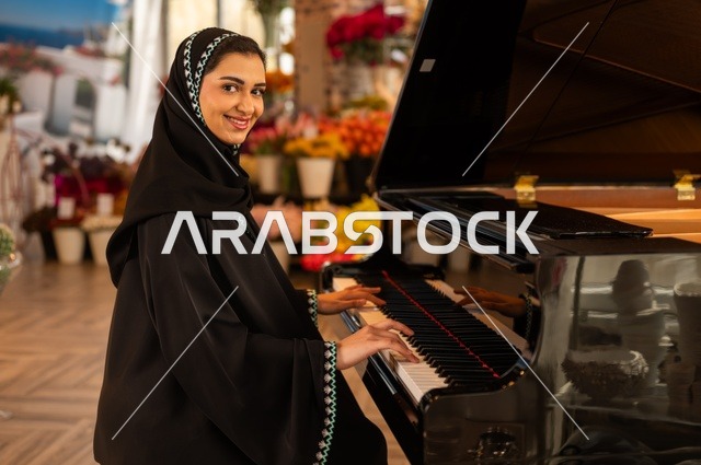 الطرب والانشطة ترفيهية، تقديم البرامج والفنون الموسيقية والفن المسرحي، إمراة خليجية سعودية عربية فنانة تجلس امام آلة البيانو الموسيقية تستمتع بالعزف، مواهب فنية موسيقية، قضاء الوقت بالعزف على الألات الوترية