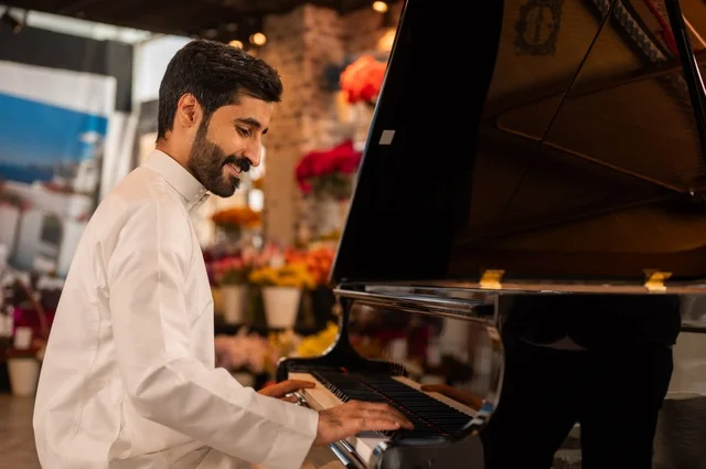 مواهب فنية موسيقية، قضاء الوقت بالعزف على الألات الوترية، الطرب والانشطة ترفيهية، تقديم البرامج والفنون الموسيقية والفن المسرحي، رجل خليجي سعودي عربي فنان يجلس امام آلة البيانو الموسيقية ويستمتع بالعزف