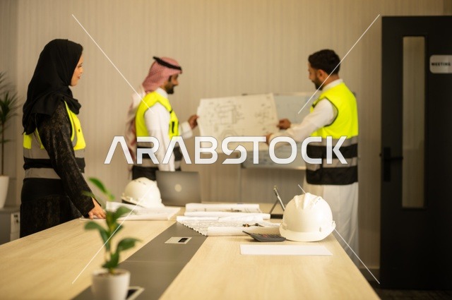 متابعة تنفيذ الخطط الهندسية الموضوعة، الشركات المختصة بورشات البناء والمقاولات، التخطيط ووضع المخططات المعمارية، مجموعة مهندسون عرب خليجيون سعوديون يعملون على مناقشة مخطط الإنشاء وتحديد القياسات بدقة داخل مقر الشركة