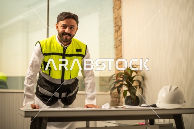 الإعمار بسواعد أبناء الوطن، مفهوم الهندسة والإنشاءات،  مهندس عربي خليجي سعودي يرتدي زي العمل يمسك بيده مخطط التطور العمراني للمباني، تدقيق ومراجعة الخطط الهندسية، دراسة أساسيات المشروع، إكمال رسم مخطوطات البناء