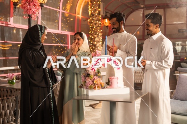 قضاء وقت ممتع مع الأهل والأصدقاء، إيماءات السعادة والمفاجأة والفرح، زينة الأعياد والمناسبات السعيدة، عائلة عرب خليجيون سعوديون يقومون بالاحتفال بعيد ميلاد صديقتهم في إحدى المطاعم السعودية، كعكة عيد ميلاد