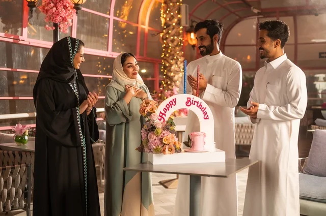 The decorations of holidays and happy occasions, gestures of happiness, surprise, and joy, Gulf Arab friends from Saudi Arabia are celebrating their friend's birthday in one of the Saudi restaurants, spending enjoyable time with family and friends, a birthday cake.