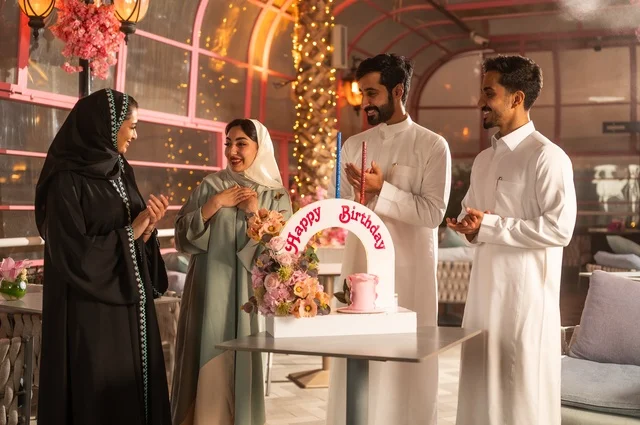 قضاء وقت ممتع مع الأهل والأصدقاء، إيماءات السعادة والمفاجأة والفرح، زينة الأعياد والمناسبات السعيدة، عائلة عرب خليجيون سعوديون يقومون بالاحتفال بعيد ميلاد صديقتهم في إحدى المطاعم السعودية، كعكة عيد ميلاد