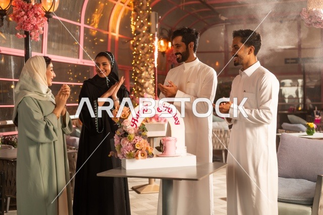 Gestures of happiness, surprise, and joy, the decorations of holidays and happy occasions, Gulf Arab friends from Saudi Arabia are celebrating their friend's birthday in one of the Saudi restaurants, spending enjoyable time with family and friends, a birthday cake.