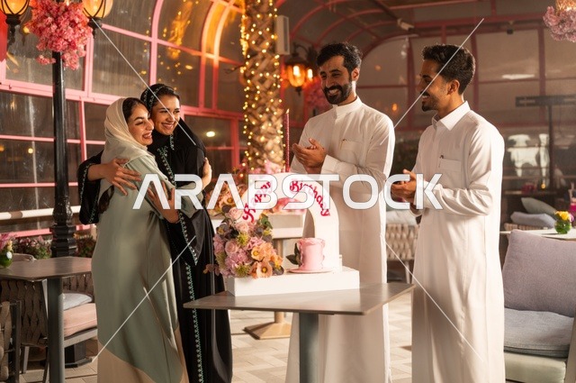 قضاء وقت ممتع مع الأهل والأصدقاء، إيماءات السعادة والمفاجأة والفرح، زينة الأعياد والمناسبات السعيدة، عائلة عرب خليجيون سعوديون يقومون بالاحتفال بعيد ميلاد صديقتهم في إحدى المطاعم السعودية، كعكة عيد ميلاد