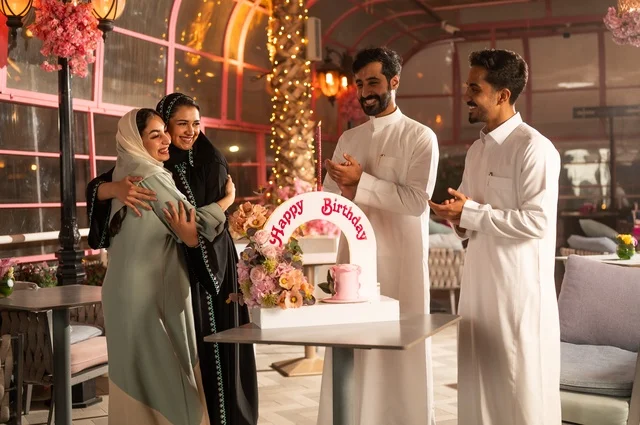 قضاء وقت ممتع مع الأهل والأصدقاء، إيماءات السعادة والمفاجأة والفرح، زينة الأعياد والمناسبات السعيدة، عائلة عرب خليجيون سعوديون يقومون بالاحتفال بعيد ميلاد صديقتهم في إحدى المطاعم السعودية، كعكة عيد ميلاد