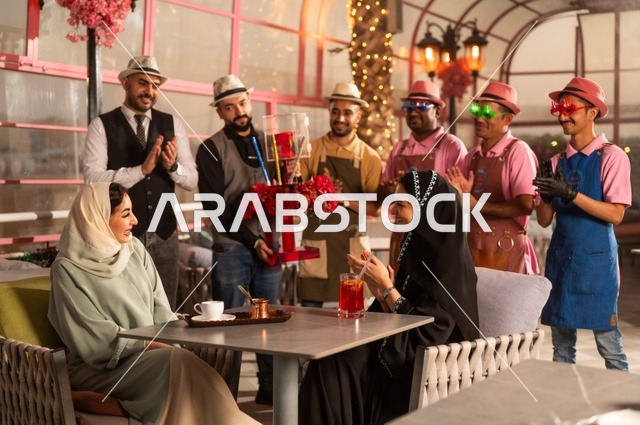 مشاركة طاقم الخدمة الاحتفال، قضاء وقت ممتع مع الأصدقاء، إيماءات السعادة والمفاجأة، امرأة عربية خليجية سعودية محجبة ترتدي العباءة تقوم بالاحتفال بعيد ميلاد صديقتها، التزيين  للاحتفال بالمناسبات السعيدة،، إقامة حفلات اعياد الميلاد في الكافيهات والمطاعم الفاخرة في المملكة