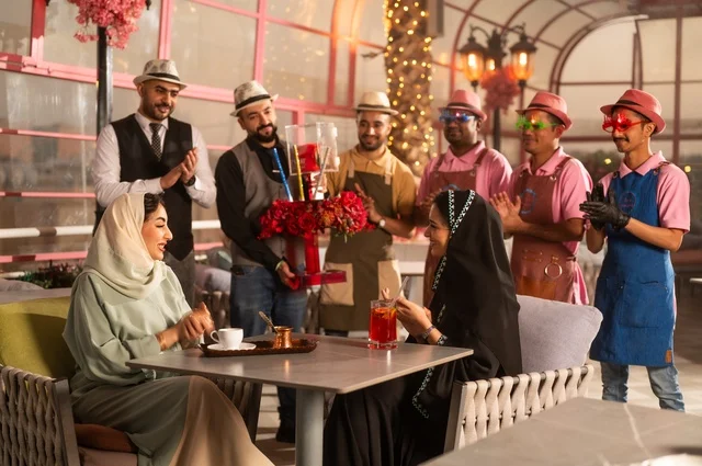 Birthday parties are held in cafes and luxury restaurants in the kingdom, with decorations to celebrate happy occasions, sharing the celebration with the service staff, spending enjoyable time with friends, gestures of happiness and surprise, an Arab Gulf Saudi woman wearing a hijab and an abaya is celebrating her friend's birthday.