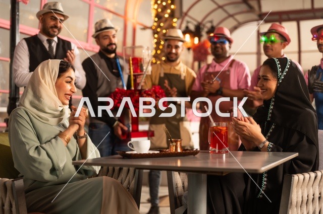 مشاركة طاقم الخدمة الاحتفال، قضاء وقت ممتع مع الأصدقاء، إيماءات السعادة والمفاجأة، امرأة عربية خليجية سعودية محجبة ترتدي العباءة تقوم بالاحتفال بعيد ميلاد صديقتها، التزيين  للاحتفال بالمناسبات السعيدة،، إقامة حفلات اعياد الميلاد في الكافيهات والمطاعم الفاخرة في المملكة