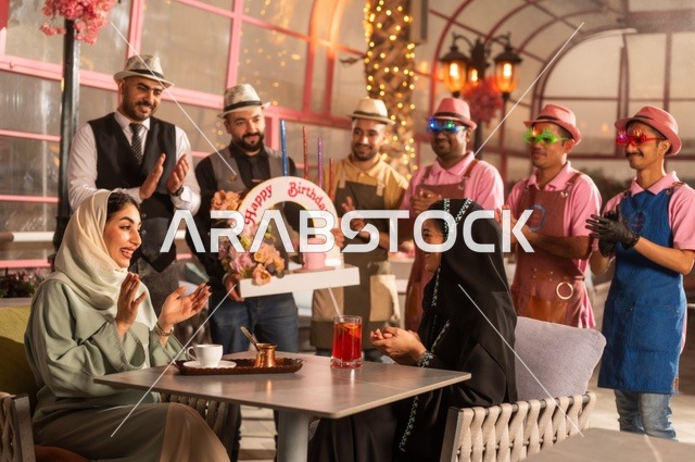 مشاركة طاقم الخدمة الاحتفال، قضاء وقت ممتع مع الأصدقاء، إيماءات السعادة والمفاجأة، امرأة عربية خليجية سعودية محجبة ترتدي العباءة تقوم بالاحتفال بعيد ميلاد صديقتها، التزيين  للاحتفال بالمناسبات السعيدة،، إقامة حفلات اعياد الميلاد في الكافيهات والمطاعم الفاخرة في المملكة