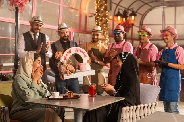 Birthday parties are held in cafes and luxury restaurants in the kingdom, with decorations to celebrate happy occasions, sharing the celebration with the service staff, spending enjoyable time with friends, gestures of happiness and surprise, an Arab Gulf Saudi woman wearing a hijab and an abaya is celebrating her friend's birthday.