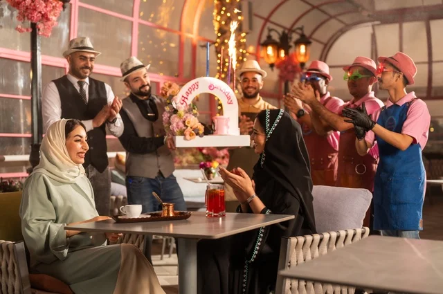 Birthday parties are held in cafes and luxury restaurants in the kingdom, with decorations to celebrate happy occasions, sharing the celebration with the service staff, spending enjoyable time with friends, gestures of happiness and surprise, an Arab Gulf Saudi woman wearing a hijab and an abaya is celebrating her friend's birthday.