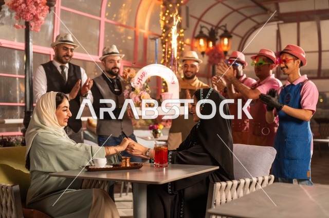 مشاركة طاقم الخدمة الاحتفال، قضاء وقت ممتع مع الأصدقاء، إيماءات السعادة والمفاجأة، امرأة عربية خليجية سعودية محجبة ترتدي العباءة تقوم بالاحتفال بعيد ميلاد صديقتها، التزيين  للاحتفال بالمناسبات السعيدة،، إقامة حفلات اعياد الميلاد في الكافيهات والمطاعم الفاخرة في المملكة