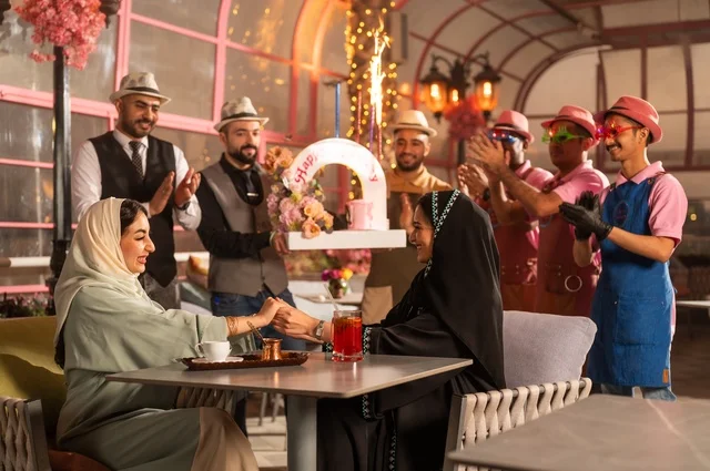 مشاركة طاقم الخدمة الاحتفال، قضاء وقت ممتع مع الأصدقاء، إيماءات السعادة والمفاجأة، امرأة عربية خليجية سعودية محجبة ترتدي العباءة تقوم بالاحتفال بعيد ميلاد صديقتها، التزيين  للاحتفال بالمناسبات السعيدة،، إقامة حفلات اعياد الميلاد في الكافيهات والمطاعم الفاخرة في المملكة