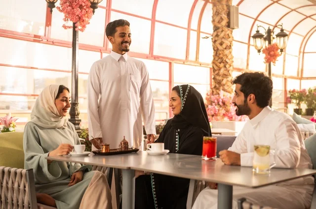 الاستمتاع بتناول المشروبات الساخنة، حوارات ونقاشات عائلية، قضاء وقت ممتع في الخارج، مفهوم الألفة والمحبة بين الأهل والأصدقاء, اصدقاء عرب خليجيون سعوديون يجلسون في احدى الكافيهات الراقية، ايماءات السعادة والسرور