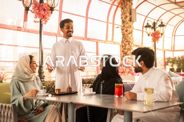 Enjoying hot drinks, family conversations and discussions, spending quality time outside, the concept of intimacy and love between family and friends, Saudi Gulf Arab friends sitting in an upscale café, gestures of happiness and pleasure