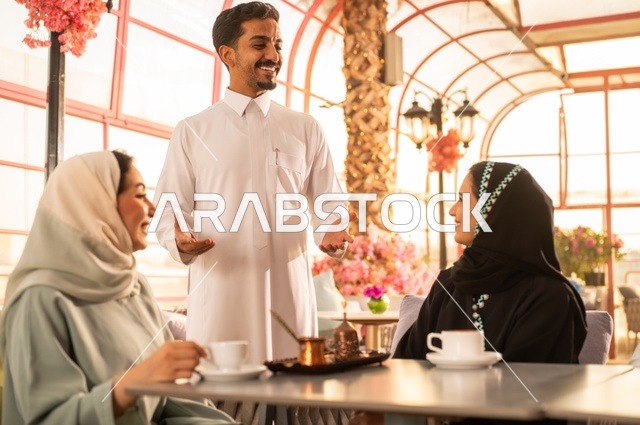 قضاء وقت ممتع في الخارج، الاستمتاع بتناول المشروبات الساخنة، حوارات ونقاشات عائلية، مفهوم الألفة والمحبة بين الأهل والأصدقاء, اصدقاء عرب خليجيون سعوديون يجلسون في احدى الكافيهات الراقية، ايماءات السعادة والسرور