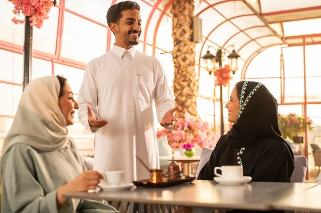 قضاء وقت ممتع في الخارج، الاستمتاع بتناول المشروبات الساخنة، حوارات ونقاشات عائلية، مفهوم الألفة والمحبة بين الأهل والأصدقاء, اصدقاء عرب خليجيون سعوديون يجلسون في احدى الكافيهات الراقية، ايماءات السعادة والسرور